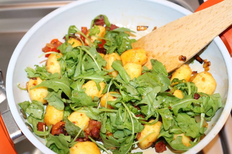 Pfanne vom Herd nehmen und den frischen Ruccola unterheben.