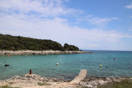 Bootsstege, türkisfarbenes Wasser und die felsige Küsten prägen das Bild an der Ostküste Istriens
